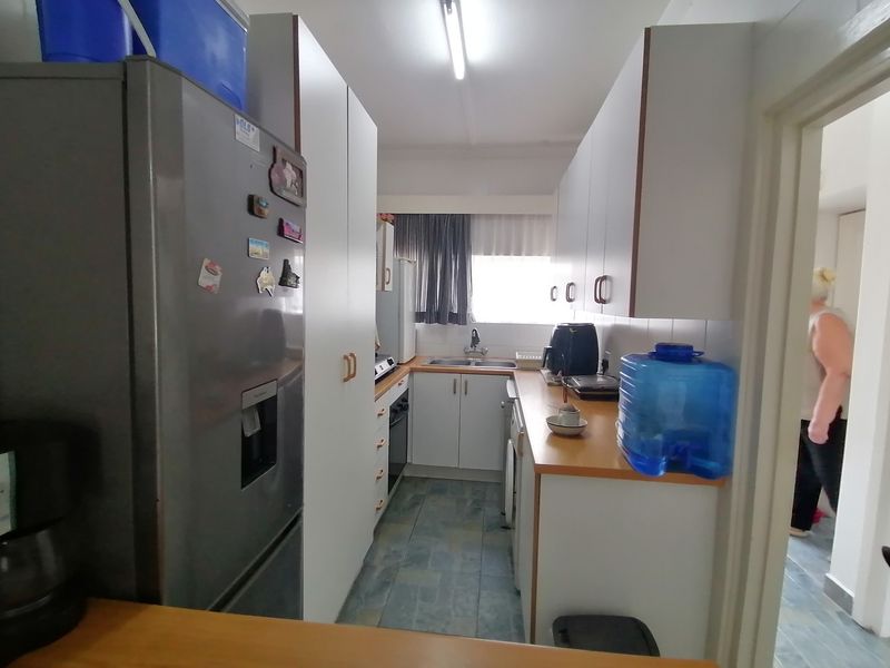 A functional galley-style kitchen featuring white cabinetry, laminate countertops, and tiled flooring, offering a practical layout for daily meal preparation.
