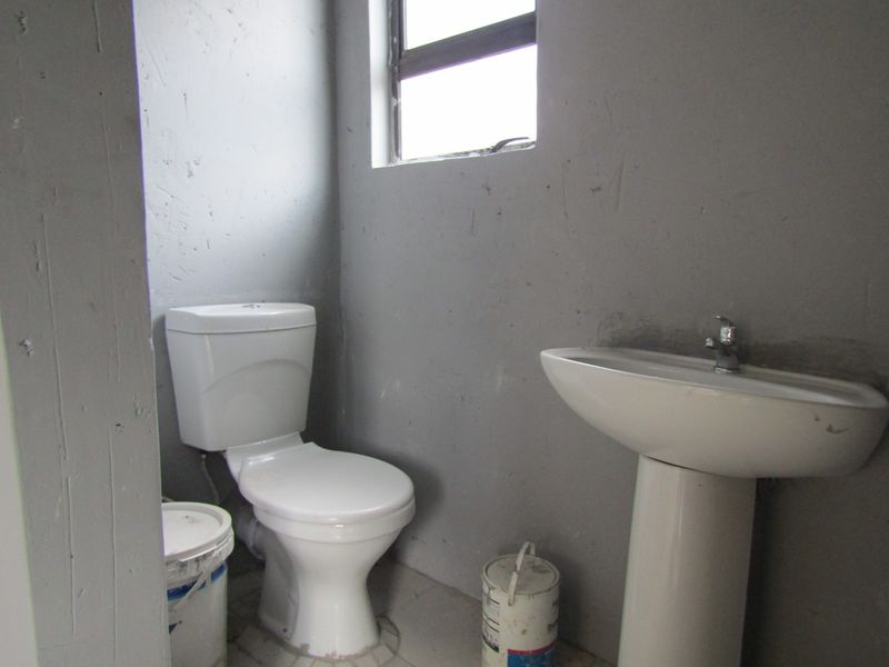 A small bathroom in shell condition featuring a pedestal basin and toilet, requiring wall finishing and final touches to complete the space.