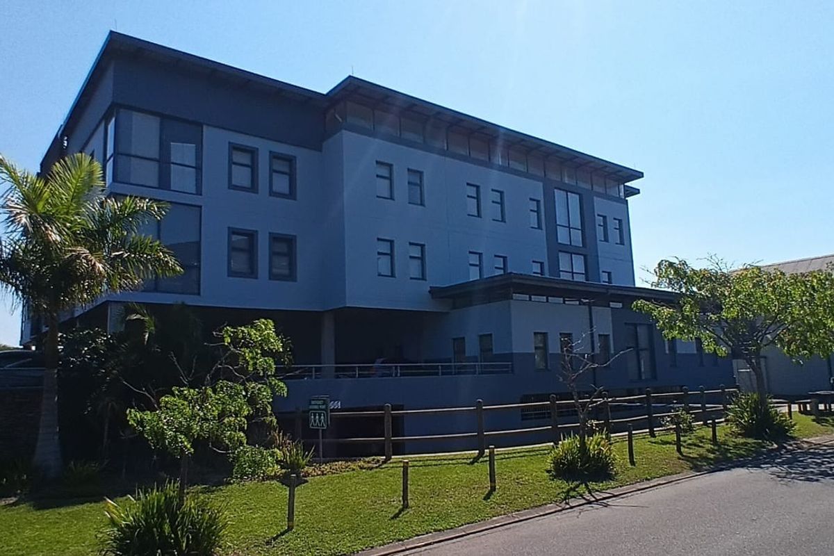 A modern multi-story office building exterior featuring a contemporary facade, timber fencing, and well-maintained surrounding landscaping.
