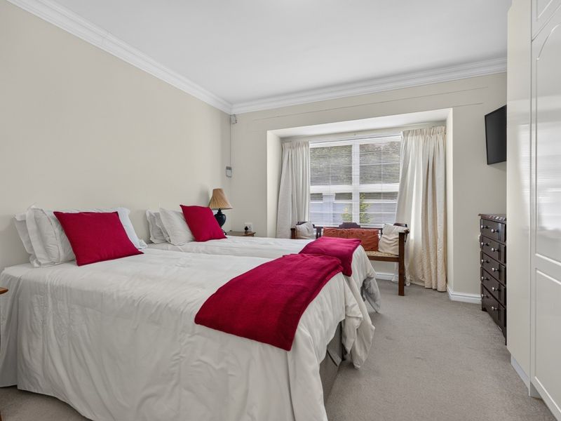 A well-lit bedroom featuring a bay window, crown molding, and a built-in wardrobe, offering a comfortable and functional living space.
