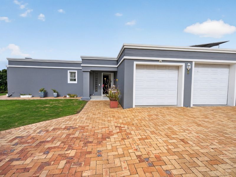 Front elevation of a modern house featuring a double garage, paved driveway, and a covered entrance with glass block detailing.