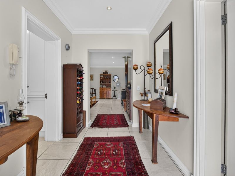 A bright and welcoming entrance hallway featuring neutral wall tones, tiled flooring, and elegant crown molding, leading through to the main living areas.