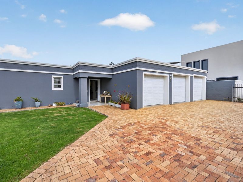 Front exterior view of a modern home featuring a triple garage, paved driveway, and well-maintained lawn.