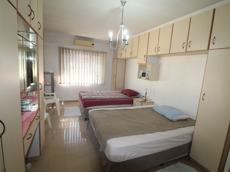 Bedroom featuring extensive built-in cabinetry, tiled flooring, and a wall-mounted air conditioning unit, providing ample storage and climate control.