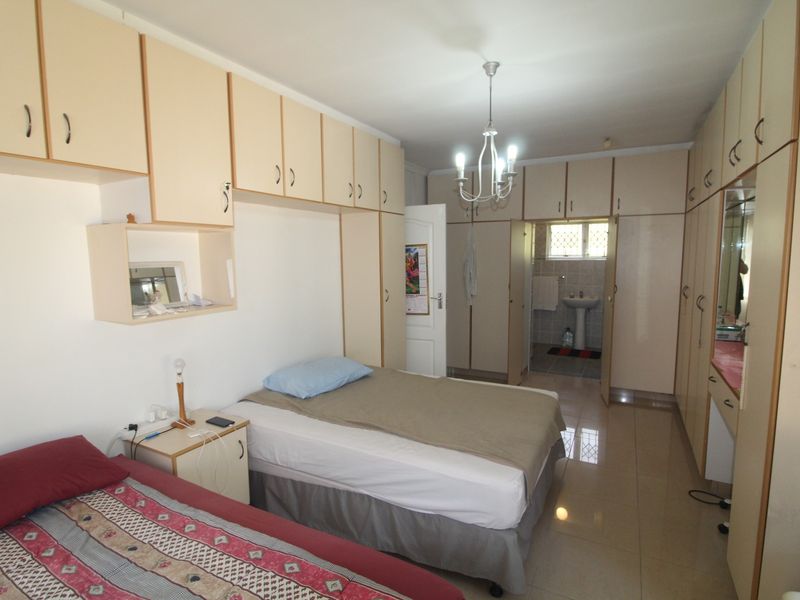 Spacious bedroom featuring extensive built-in cabinetry, tiled flooring, and direct access to an en-suite bathroom.