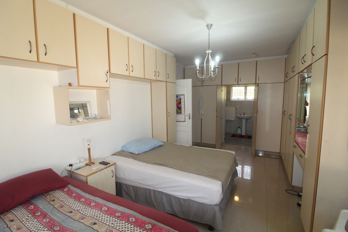 Spacious bedroom featuring extensive built-in cabinetry, tiled flooring, and direct access to an en-suite bathroom.