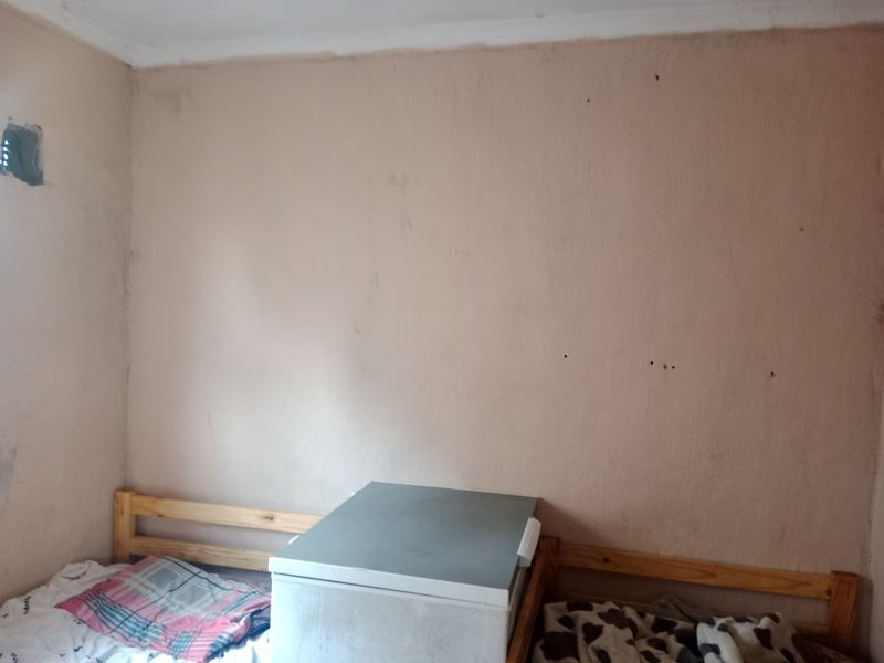 A bedroom space featuring plain walls with visible surface wear and scuffing, requiring cosmetic updates to improve the overall finish.