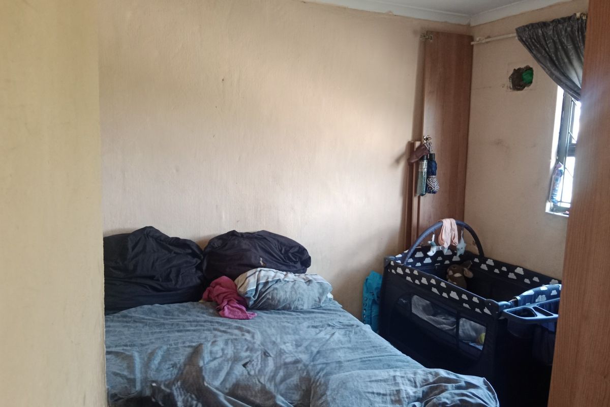 A bedroom featuring a built-in cupboard and window, currently requiring maintenance and cosmetic updates to the wall finishes and electrical fixtures.