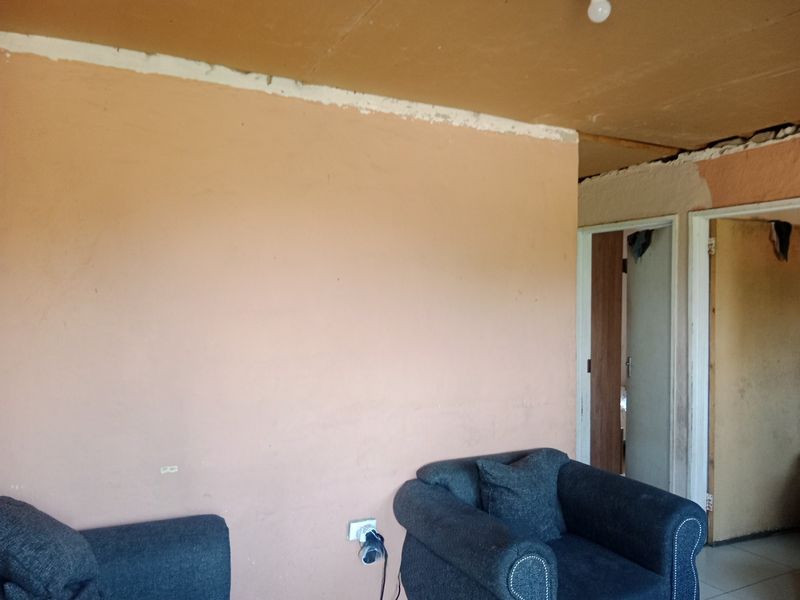 A living area featuring unfinished ceiling edges and wall surfaces, requiring cosmetic repairs and finishing to improve the overall aesthetic and condition.