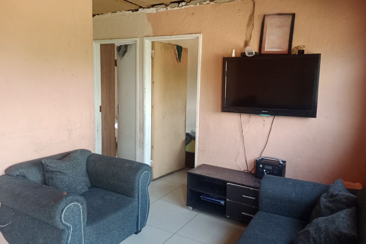 A living room area featuring tiled flooring and internal doors, currently requiring significant cosmetic repairs to the walls and ceiling.