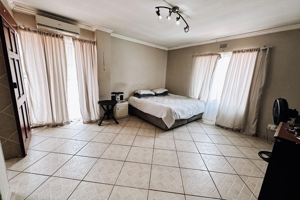 Spacious bedroom featuring tiled flooring, air conditioning, and large windows with curtain rails, offering a neutral canvas for personalization.