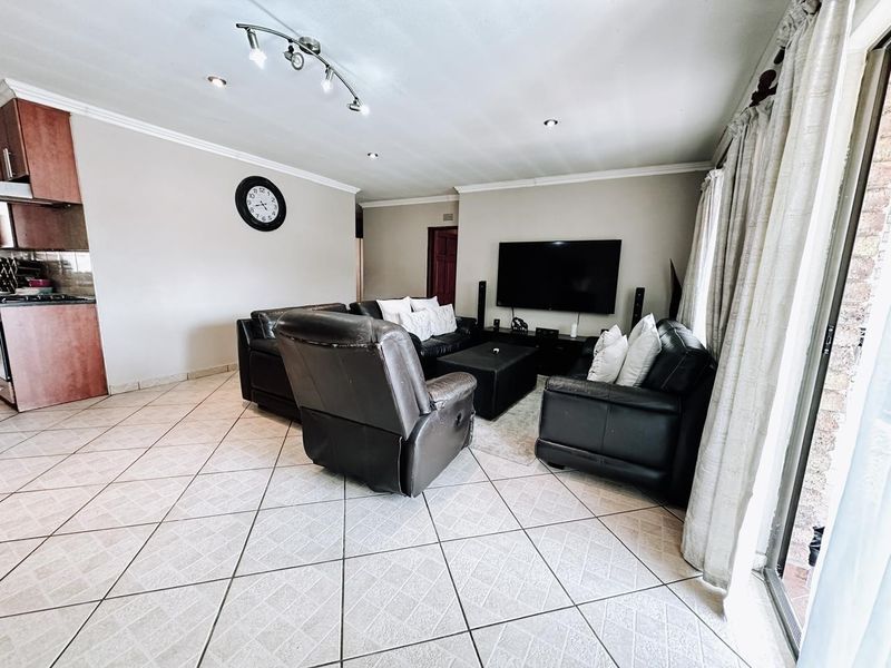 Open-plan living area featuring tiled flooring, recessed lighting, and an integrated kitchen space with direct access to an outdoor area via sliding doors.