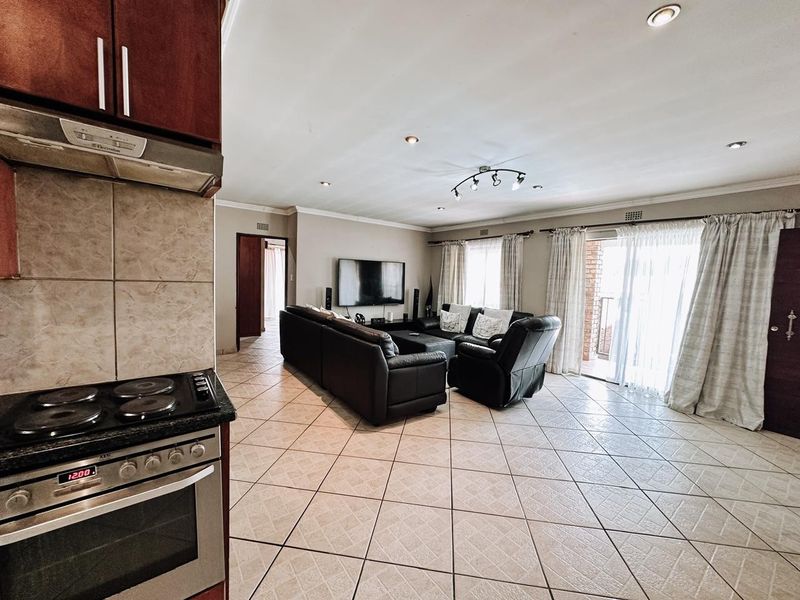 An open-plan living and kitchen area featuring tiled flooring, built-in kitchen appliances, and sliding glass doors leading to an outdoor space.