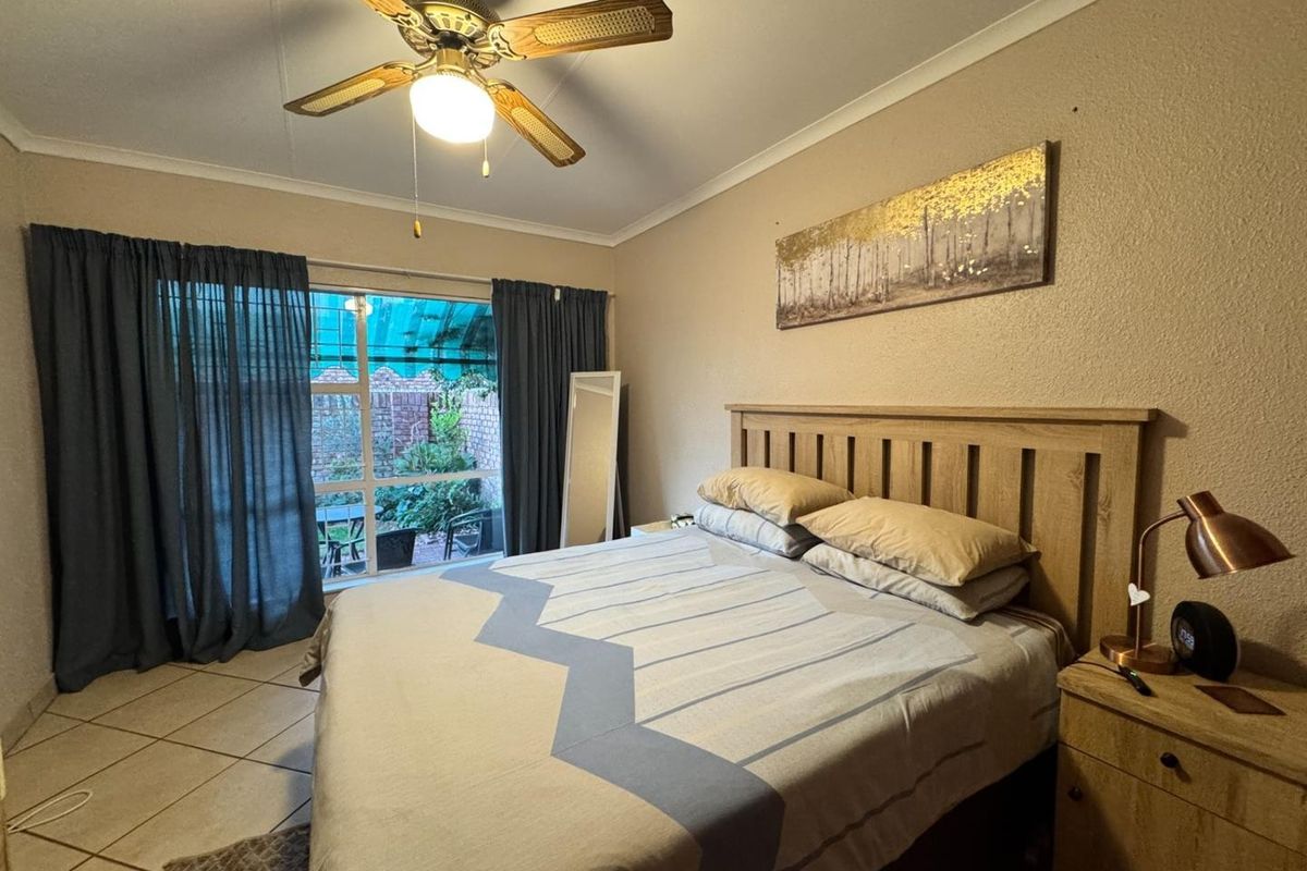 A bedroom featuring tiled flooring, a ceiling fan, and a sliding glass door providing access to an outdoor patio area.