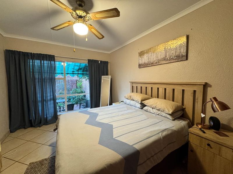 A bedroom featuring tiled flooring, a ceiling fan, and a sliding glass door providing access to an outdoor patio area.