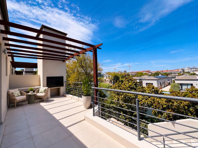 Spacious balcony featuring a timber pergola, tiled flooring, and a metal balustrade, offering scenic views of the surrounding estate and water.