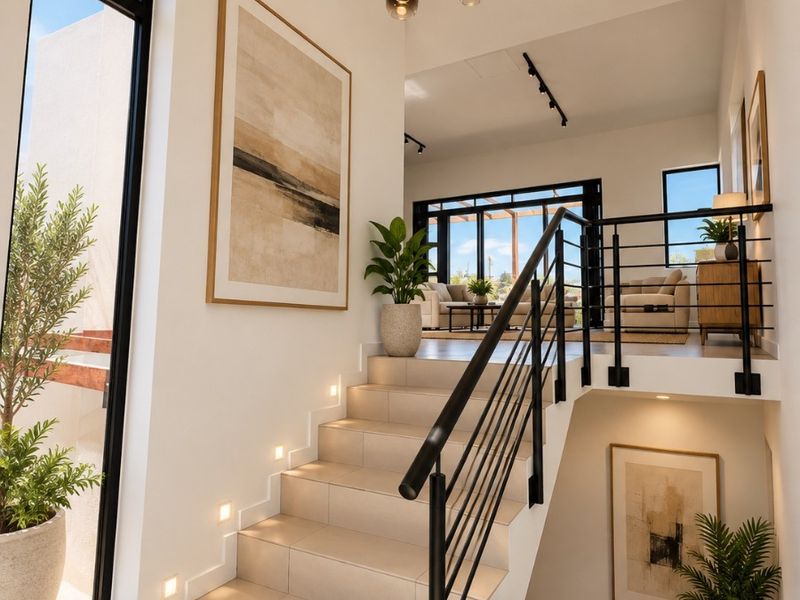 Modern split-level entry featuring a tiled staircase with integrated lighting, black metal railings, and high ceilings with contemporary pendant lighting.