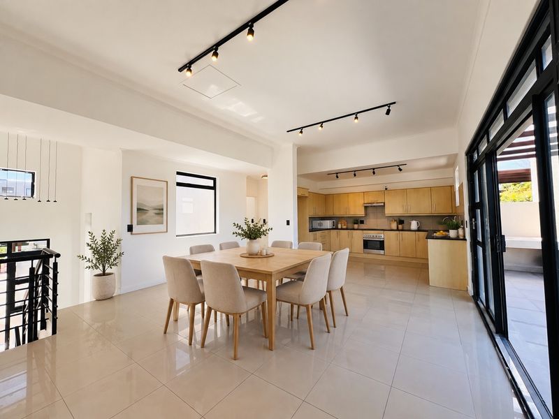 Spacious open-plan living and dining area featuring modern track lighting, tiled floors, and a well-appointed kitchen with built-in cabinetry and appliances.