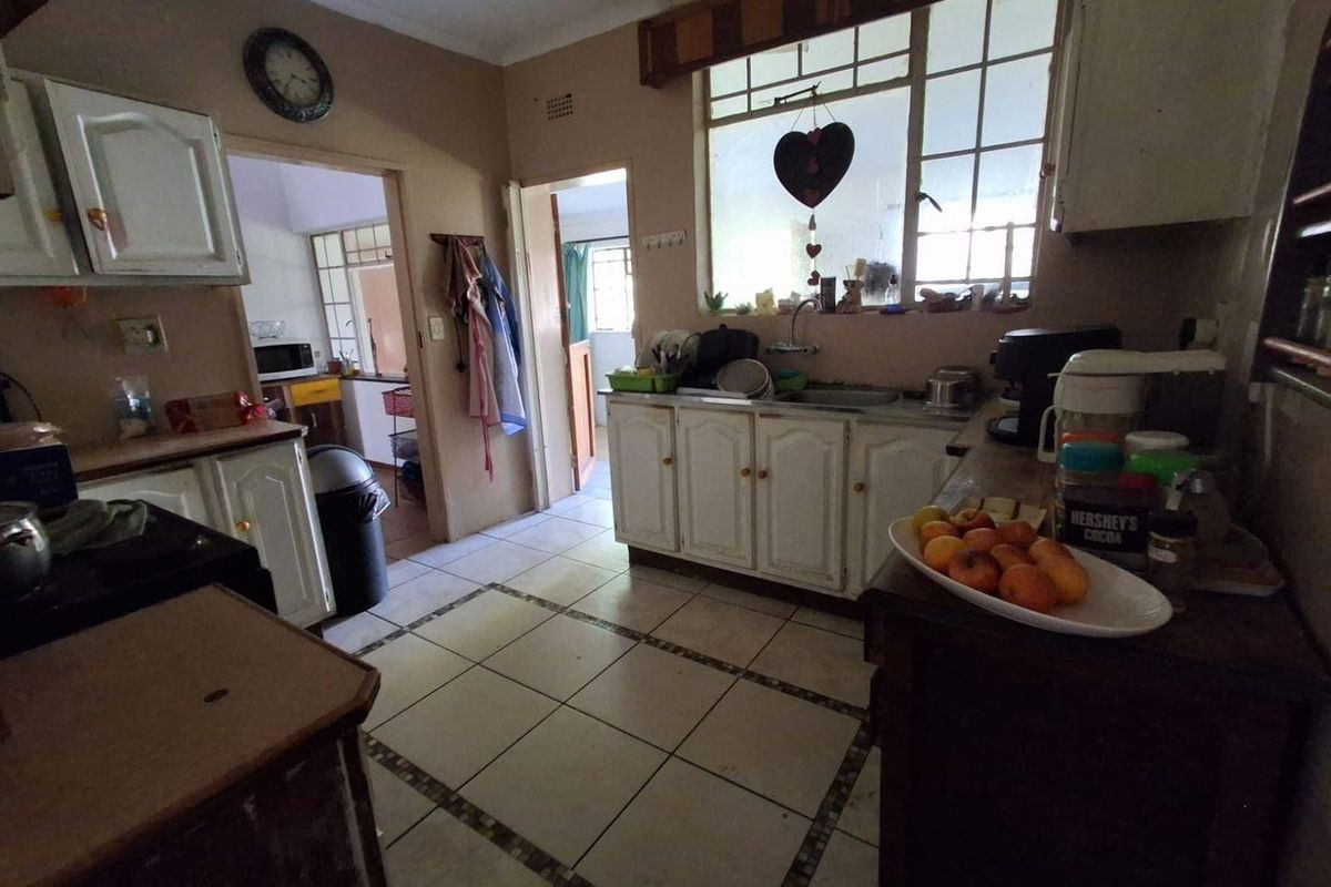 A functional kitchen space featuring traditional cabinetry, tiled flooring, and a window above the sink area, offering potential for modernization and cosmetic updates.