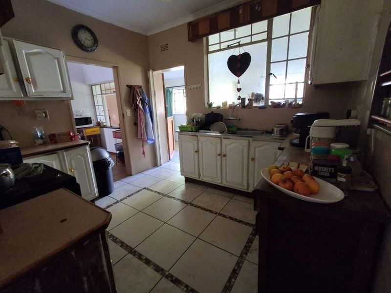 A functional kitchen space featuring traditional cabinetry, tiled flooring, and a window above the sink area, offering potential for modernization and cosmetic updates.