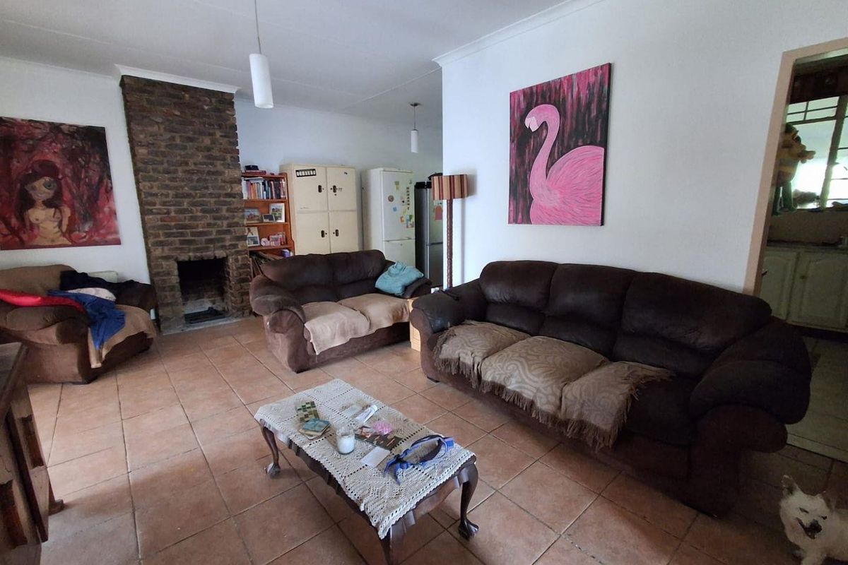 A living room featuring a prominent brick fireplace and tiled flooring, offering a functional space with potential for modern updates.