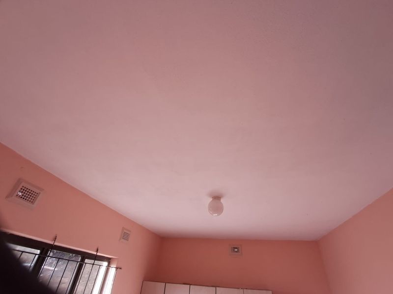 A view of a room interior focusing on the ceiling, featuring a central light fixture and multiple ceiling ventilation grilles.