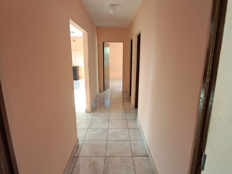 A clean, empty hallway featuring neutral tiled flooring and access to multiple rooms, providing a functional transition space within the home.