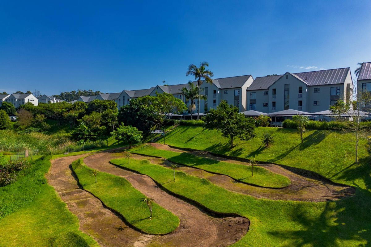 Aerial view of an apartment complex featuring well-maintained green spaces and a dedicated recreational track within the estate grounds.