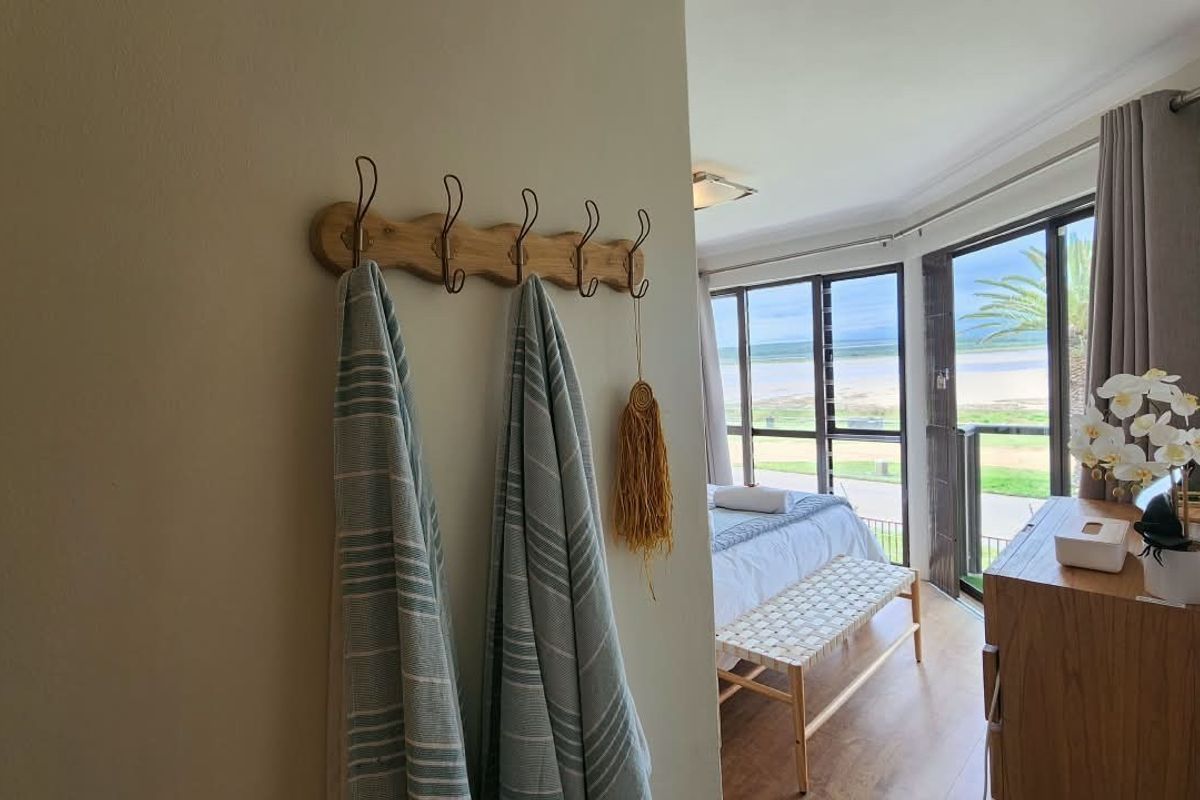 A bright bedroom featuring laminate flooring and large sliding glass doors that provide natural light and access to a balcony with scenic views.