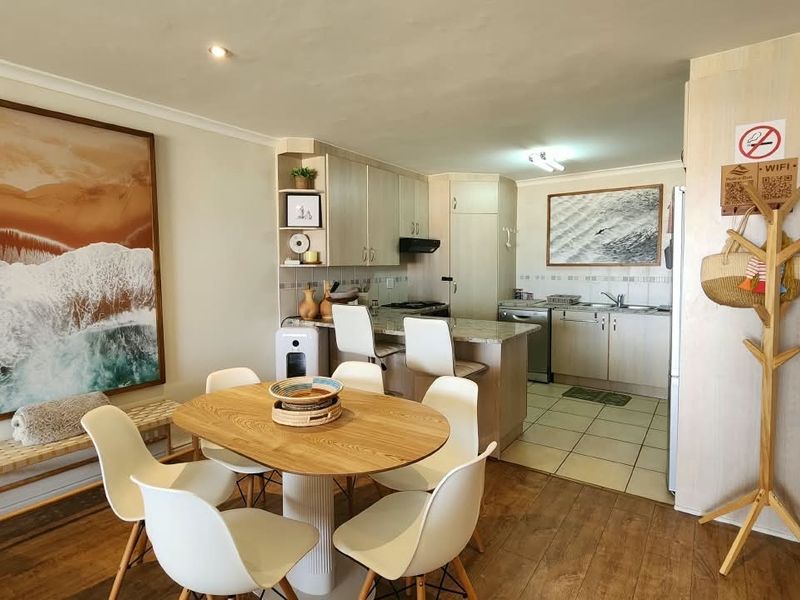 Open plan living and dining area featuring a functional kitchen with granite countertops, cabinetry, and a breakfast bar, finished with a mix of tile and laminate flooring.