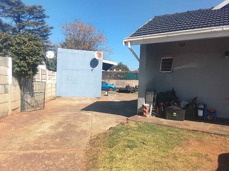 Rear exterior view of the property featuring a concrete driveway, precast boundary wall, and tiled roof structure.