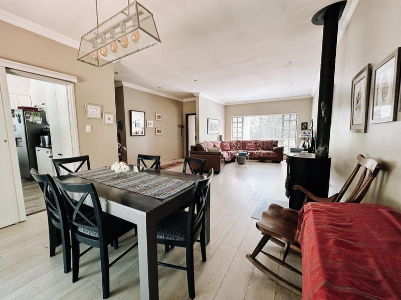 Spacious open-plan living and dining area featuring light laminate flooring, a prominent wood-burning fireplace, and modern recessed lighting throughout.