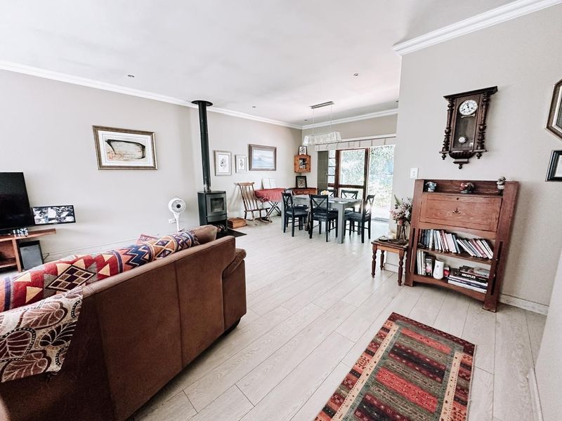 Spacious open-plan living and dining area featuring light-toned laminate flooring, a wood-burning fireplace, and sliding glass doors leading to the outdoor space.