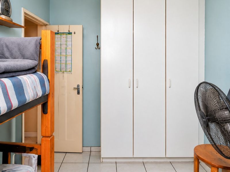 A functional bedroom featuring built-in cupboards and tiled flooring, providing a practical space with neutral wall tones.