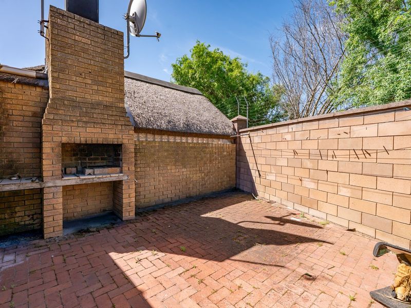 Outdoor patio area featuring a built-in brick braai, paved flooring, and a perimeter boundary wall, offering a functional space for outdoor entertaining.