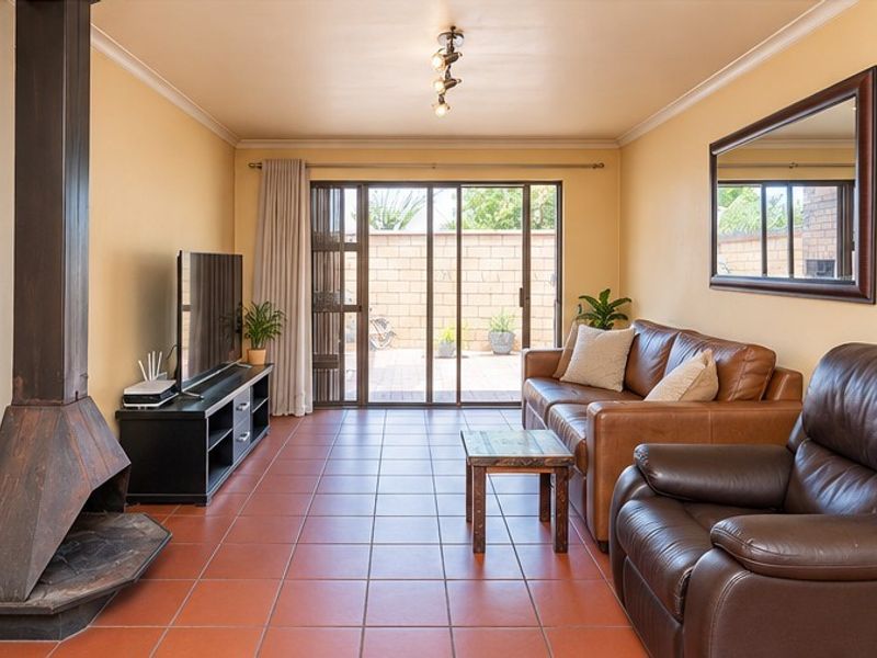 A comfortable living room featuring tiled flooring, a prominent freestanding fireplace, and sliding glass doors that provide direct access to the rear patio area.