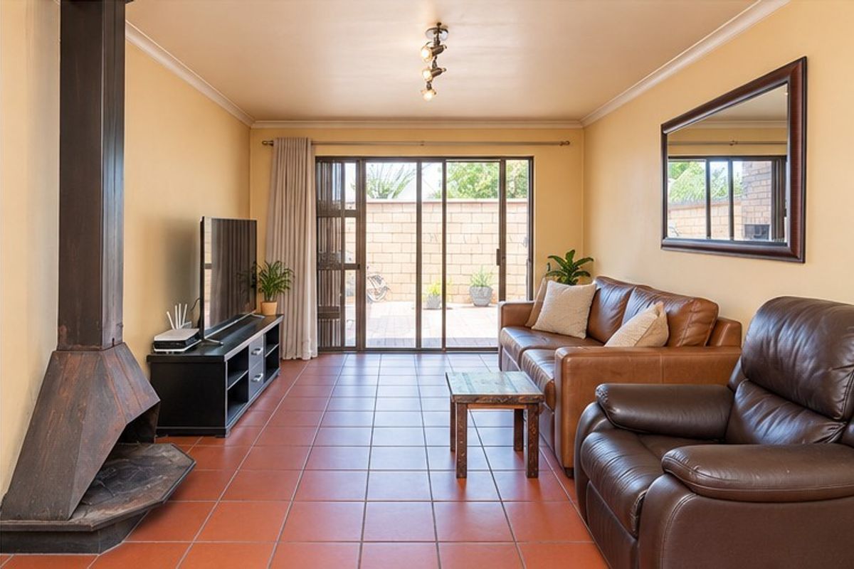 A comfortable living room featuring tiled flooring, a prominent freestanding fireplace, and sliding glass doors that provide direct access to the rear patio area.