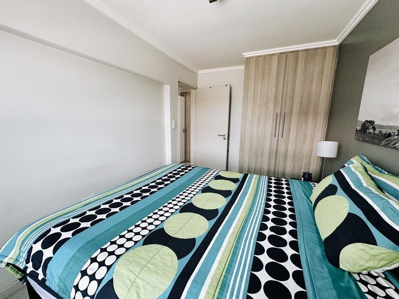 A well-maintained bedroom featuring a built-in wardrobe with wood-grain finish and classic cove cornicing.