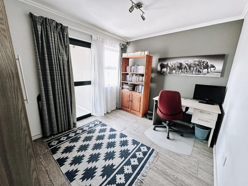 A functional bedroom featuring tiled flooring, a sliding glass door providing natural light, and a built-in wardrobe.