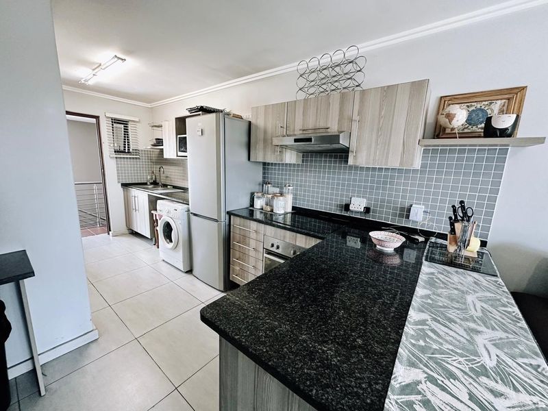 Modern kitchen featuring granite countertops, built-in cabinetry, tiled backsplash, and integrated appliances, offering a functional and well-maintained cooking space.