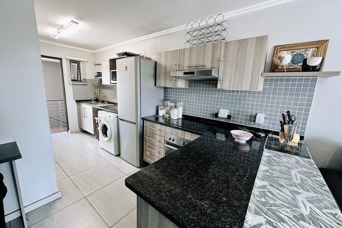 Modern kitchen featuring granite countertops, built-in cabinetry, tiled backsplash, and integrated appliances, offering a functional and well-maintained cooking space.