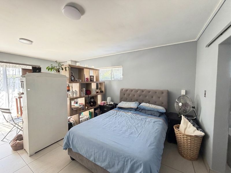A bedroom featuring tiled flooring, a sliding glass door providing natural light, and neutral wall finishes.