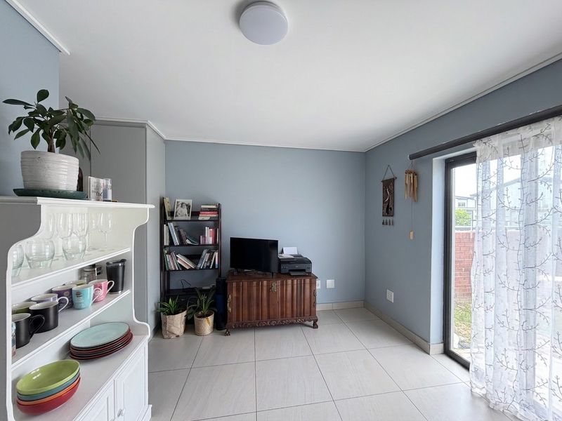 A bright living area featuring neutral tiled flooring and a sliding glass door providing access to the exterior.