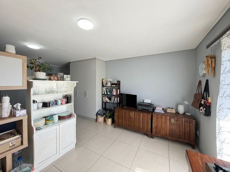 A well-maintained living area featuring neutral grey walls, light-colored floor tiles, and practical built-in storage cupboards.