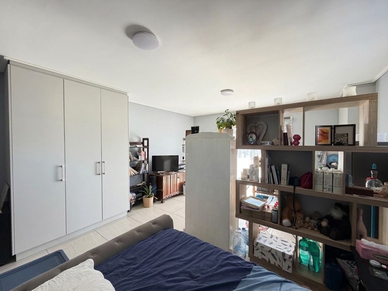 A bedroom featuring neutral walls, tiled flooring, and a large built-in wardrobe providing ample storage space.
