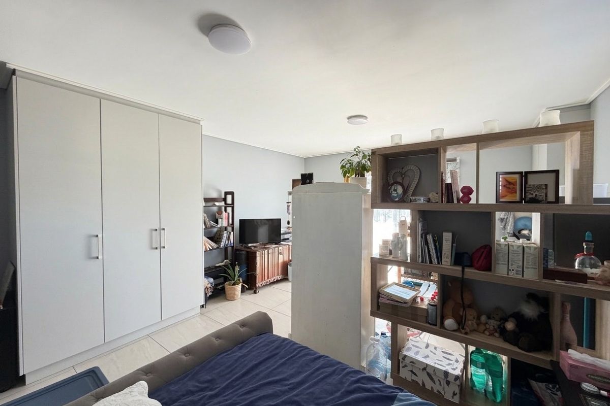 A bedroom featuring neutral walls, tiled flooring, and a large built-in wardrobe providing ample storage space.