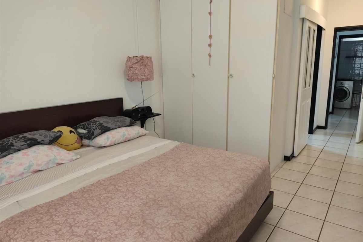 A bedroom featuring built-in cupboards and tiled flooring, with a view into an adjacent laundry area.