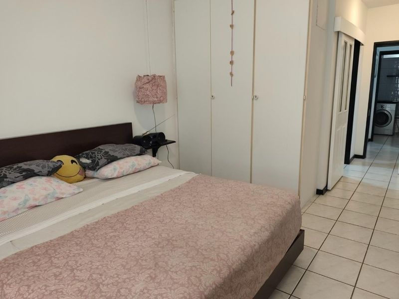 A bedroom featuring built-in cupboards and tiled flooring, with a view into an adjacent laundry area.