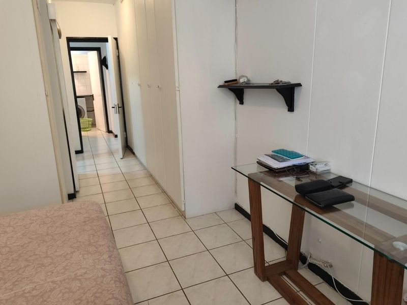 A functional hallway featuring tiled flooring and extensive built-in cupboard storage, providing a clean and practical transition space within the apartment.
