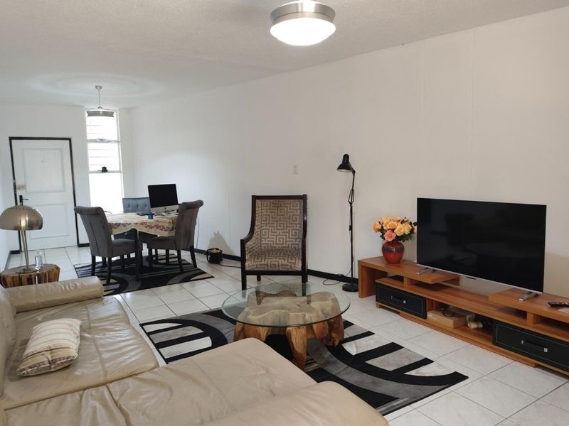 Open plan living and dining area featuring neutral tiled flooring and ample natural light from the window.